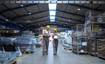 Két ember munkáról beszélget a raktárban.